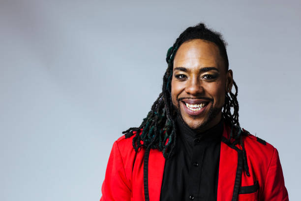 Closeup studio portrait of a man wearing a red jacket suit and dreadlocks smiling. Studio portrait of a man wearing a red jacket suit and dreadlocks. White background. Single person. non binary gender photos stock pictures, royalty-free photos & images