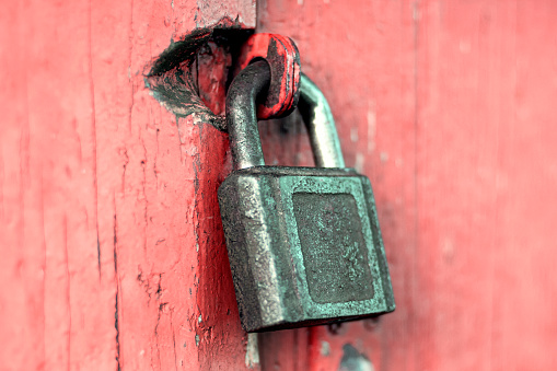 Old rusty cast iron padlock on red painted door