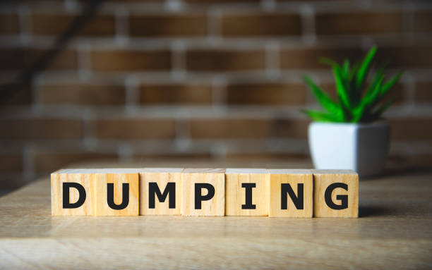 istock Dumping Word Written In Wooden Cubes on brick background . 1199544583