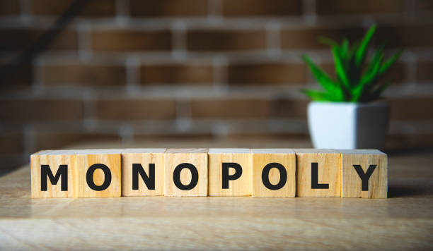istock Monopoly written on a wooden cube on brick background. 1199544584