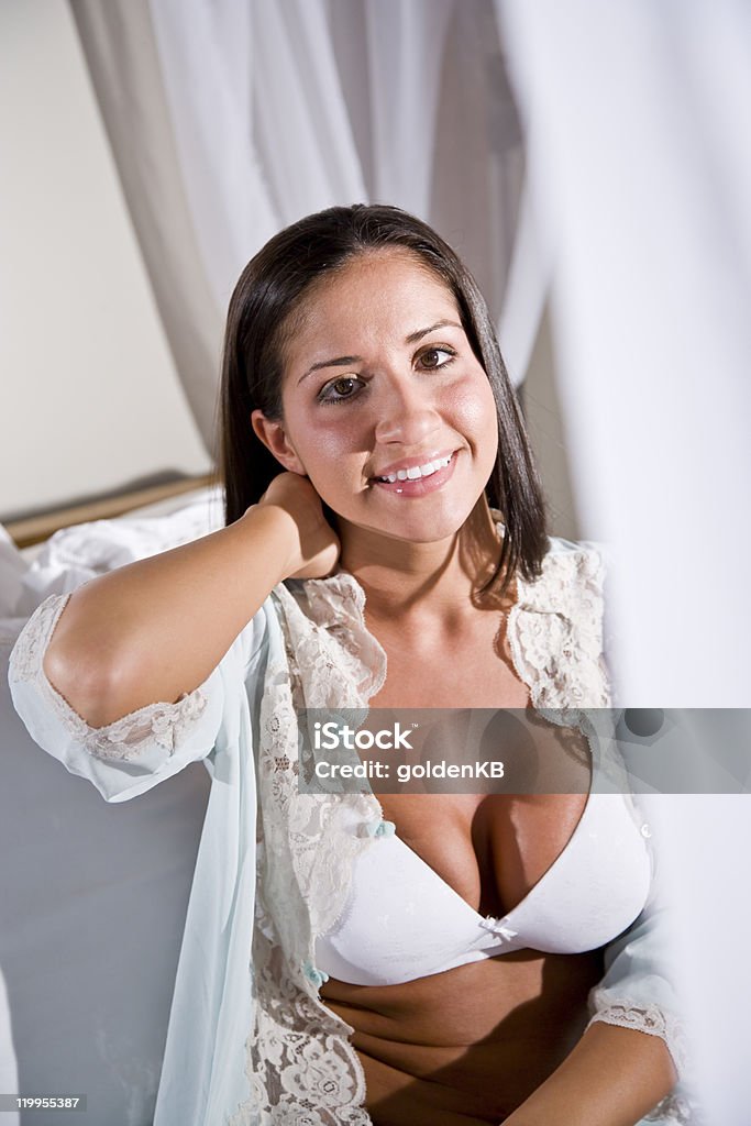 Jeune hispanique femme assise sur blanc lit à baldaquin - Photo de Lit à baldaquin libre de droits