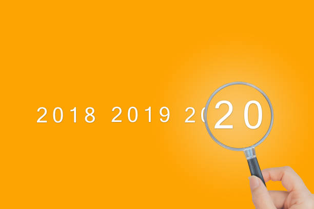 istock Female hand holding magnifying glass and looking at 2020 text words. 1199556340