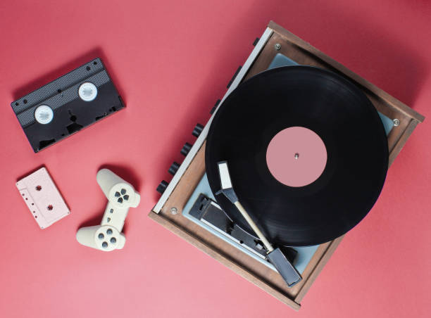 istock Retro items on a red background. Vinyl player, video, audio cassette, gamepad. Top view 1199567819