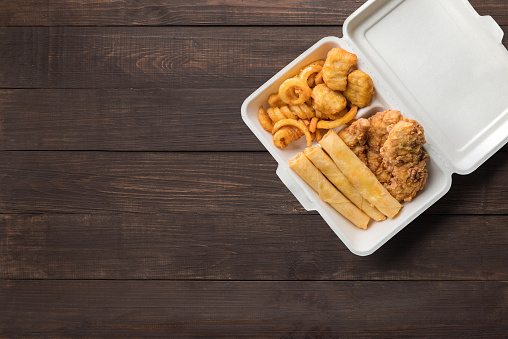 Fried chicken, french fries with cheeseburger spring rolls on wooden background. Copyspace for text and logo. Top view.