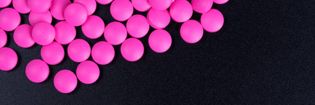 istock Pink pills are scattered on a black background. 1199569759