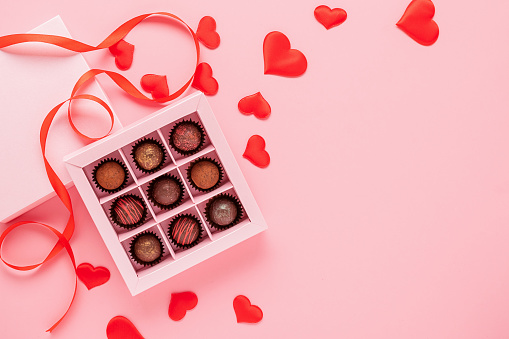 Handmade chocolates truffle in a box on a pink background with valentines. Valentines day concept festive food gifts. Horizontal frame copy space.