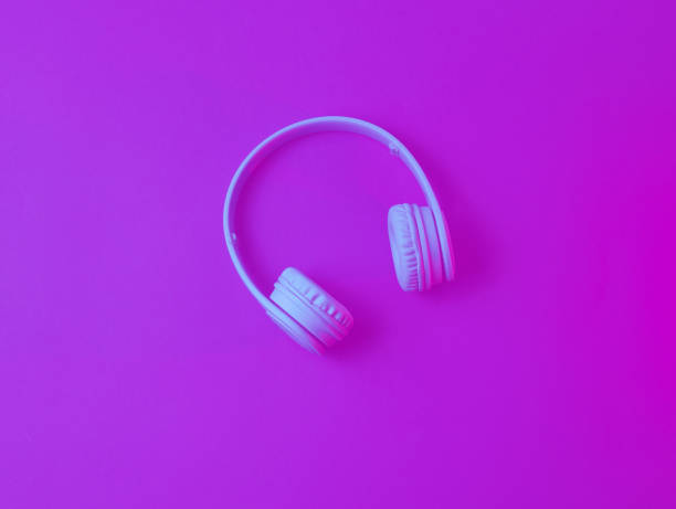 istock Wireless headphones on dark blue red background. Neon light. Duotone effect. Top view. 1199572403