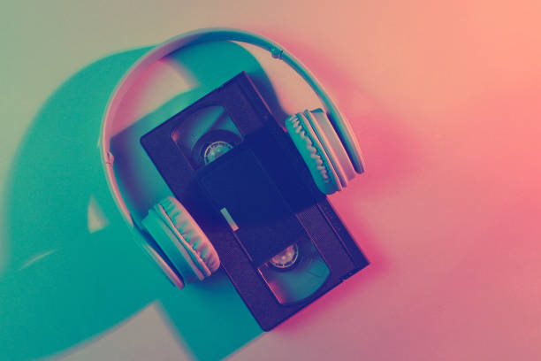 Video cassette with headphones. Retro wave, red blue neon light, ultraviolet. Top view, minimalism
