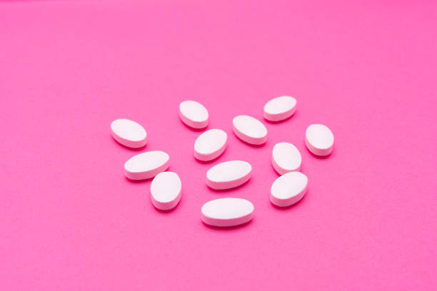 istock White oval pills lie on a pink background. Copy space, macro 1199584159