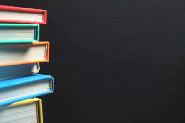 Close-up on Stack of Books Against Blank Blackboard Background.