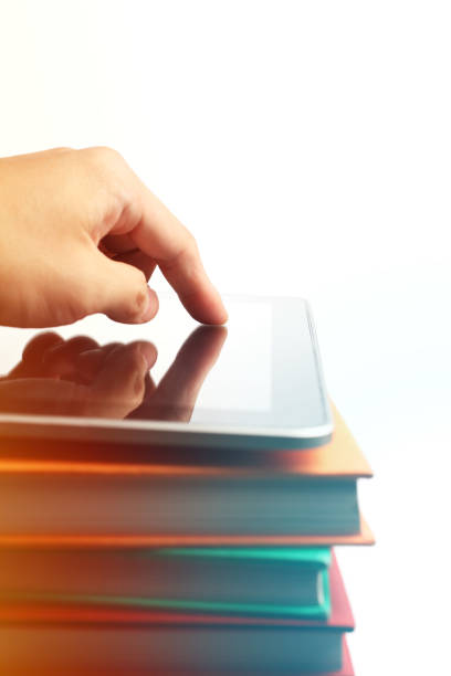 Hand Pressing the Screen of Digital Tablet on a Stack of Books with White Background.