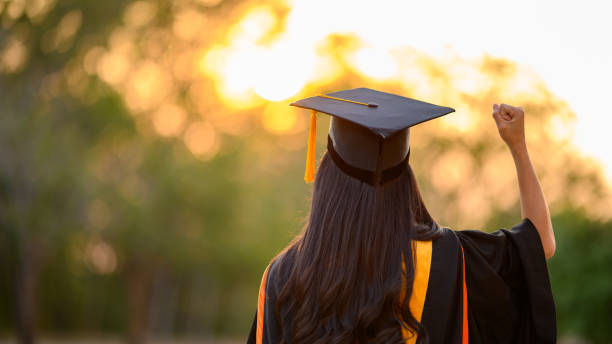 las graduadas llevan vestidos negros y taslas amarillas esperando para asistir a la ceremonia de inicio en la universidad. - toga fotografías e imágenes de stock