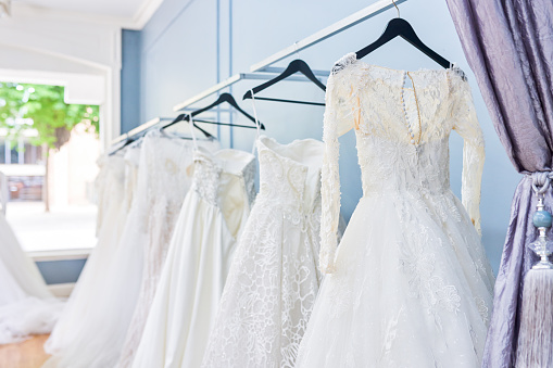 Cropped shot of wedding dresses hanging on a railing in a bridal shop