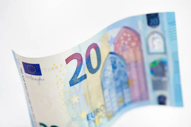 High resolution photograph of a bent 20 Euro bill in front of a white background.