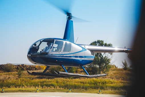 modern, gray, two-seater, small, helicopter, open doors, grassy airfield,