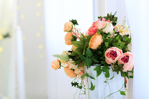 Beautiful flower arrangement with many pink and white roses in a golden painted flower pot
