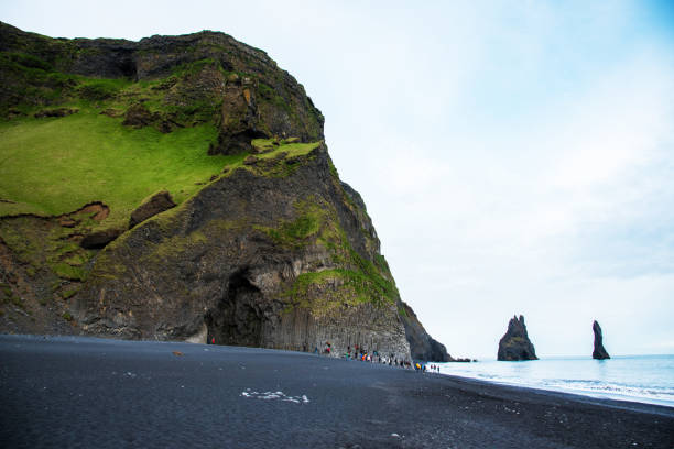 istock Beautiful dramatic landscape with cave in basalt rock on the black sand beach on Reynisdrangar Sea Cliffs, stones called Troll under the Reynisfjall Mountain near Vik, Iceland. Exotic countries. 1199606615