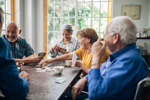 istock Senior friends having fun playing cards together 1199607733