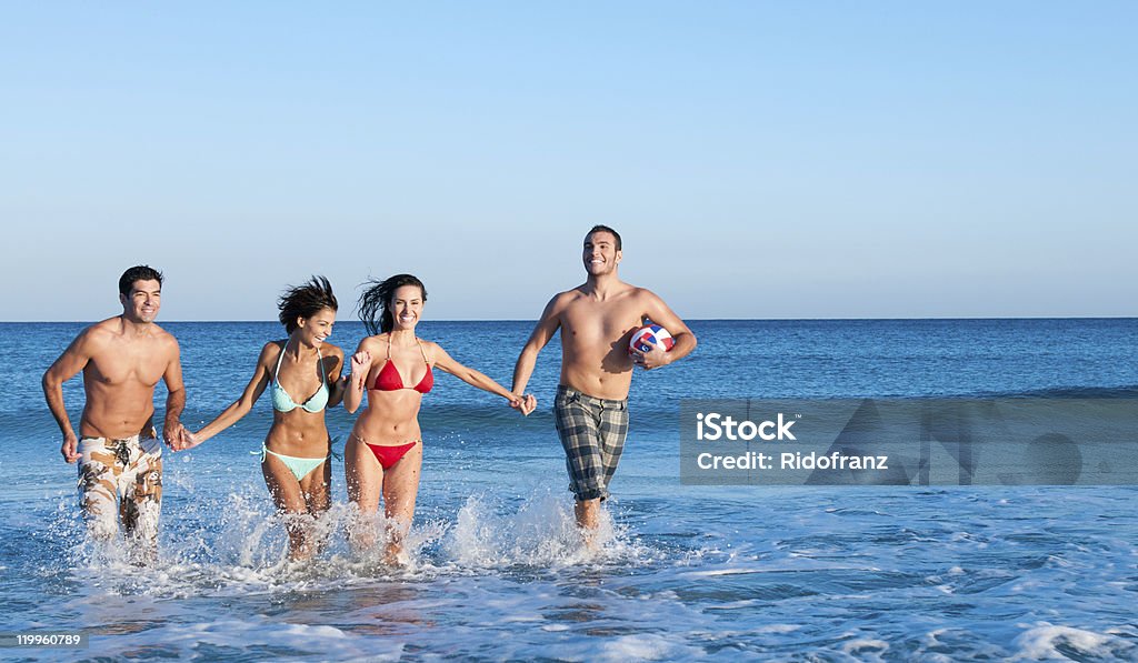 Sonriendo amigos jugando en la playa - Foto de stock de 20 a 29 años libre de derechos