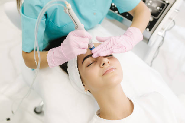 Professional female cosmetologist doing Hydradermabrasian procedure in Cosmetology clinic. Doctor use hydra vacuum cleaner. Rejuvenation And Hydratation. Cosmetology stock photo