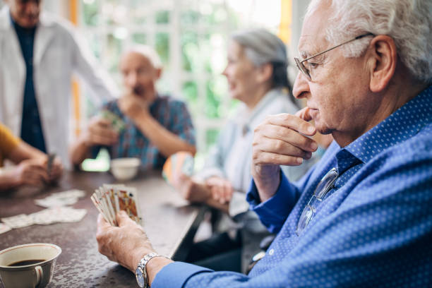 istock Senior gentleman playing cards with friends 1199610604