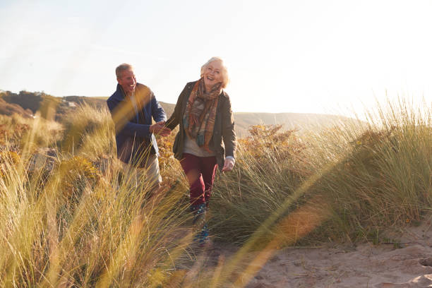 istock Loving Active Senior Couple Holding Hands As They Walk Through Sand Dunes 1199611990