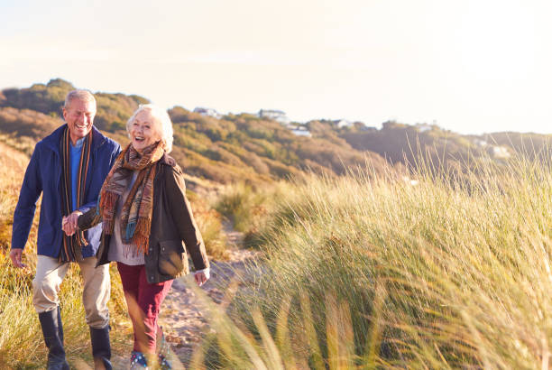 istock Loving Active Senior Couple Holding Hands As They Walk Through Sand Dunes 1199612015