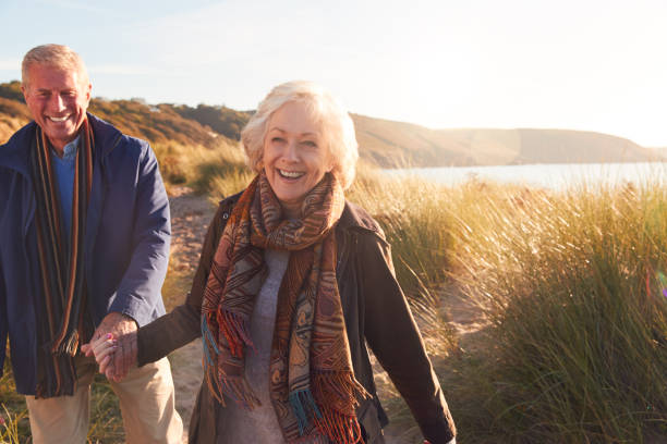 istock Loving Active Senior Couple Holding Hands As They Walk Through Sand Dunes 1199612032