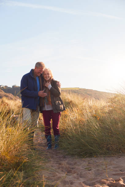 istock Loving Active Senior Couple Hugging As They Walk Through Sand Dunes 1199612114