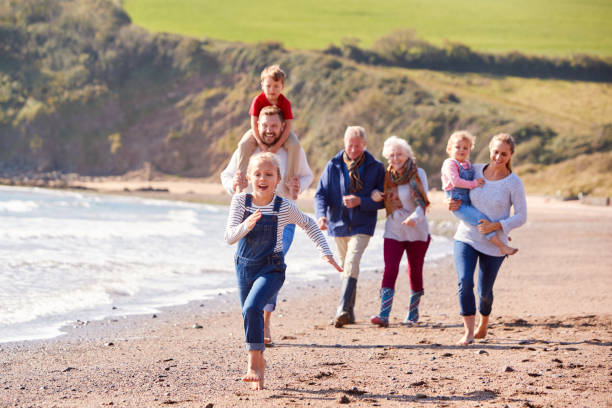 mehrgenerationenfamilie zu fuß entlang der küste von beach by waves together - family grandmother multi generation family nature stock-fotos und bilder