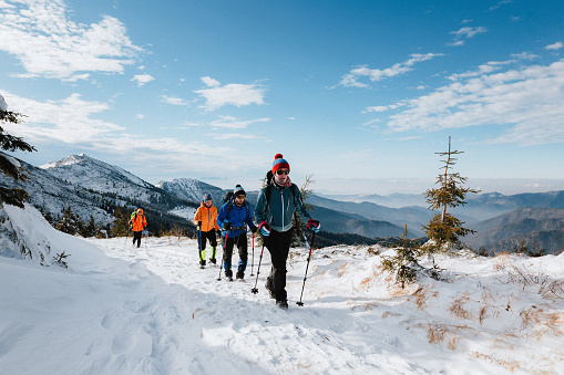 Caminata de invierno de cuatro turistas en las montañas en equipo completo en tiempo soleado photo