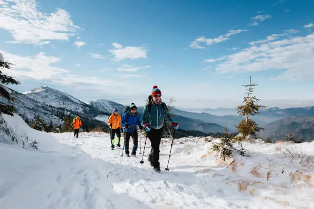 Winter hike of four tourists in the mountains in full equipment in sunny weather