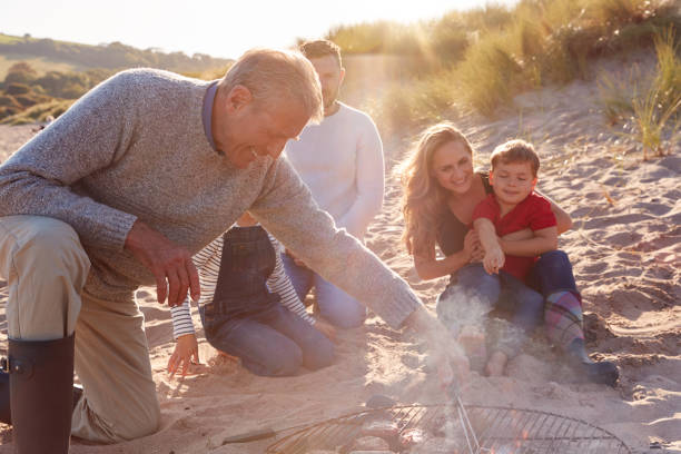 istock Grandfather Cooking As Multi-Generation Family Having Evening Barbecue Around Fire On Beach Vacation 1199617504