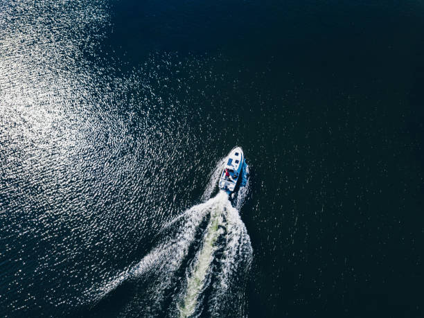 vista aerea di motoscafo o yacht al mare blu o al lago lasciando una scia - recreational boat motorboat speedboat aerial view foto e immagini stock