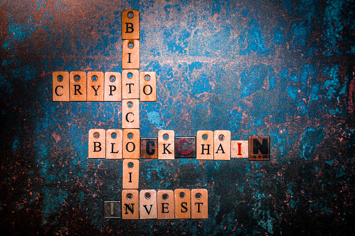 Color image depicting a selection of words related to cryptocurrency - such as bitcoin, invest, crypto and blockchain - arranged on a rusted metallic background. Room for copy space.