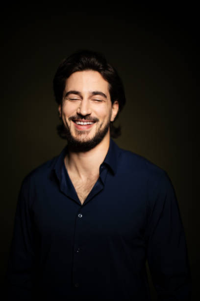 istock Portrait of young man smiling on dark background 1199617832