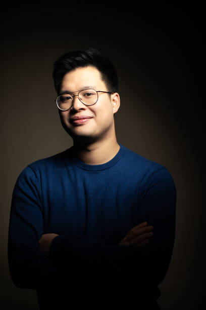 istock Confident asian man standing on dark background 1199617898