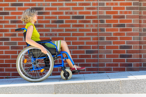 adult woman on wheelchair entering the platform or driveway - side view