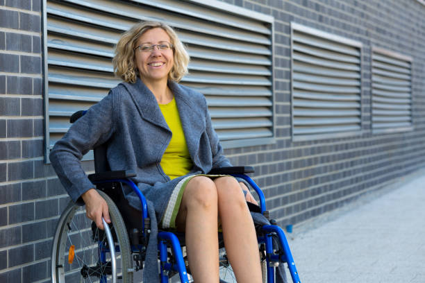 young adult woman on wheelchair on the street stock photo