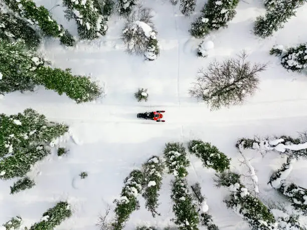 Aerial view of red snowmobile in snow covered winter forest in rural Finland, Lapland