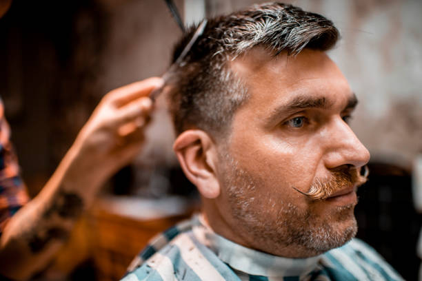 istock Modern barber using scissors to cut a man's hair in a barber salon 1199620992