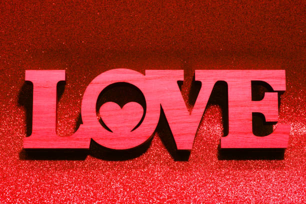 Valentine decoration (LOVE sign with a heart) on a sparkling background. Toned in red color.