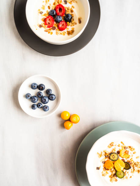 istock Two cereal bowls with yoghurt, fresh raspberries and blueberries on a table 1199624510