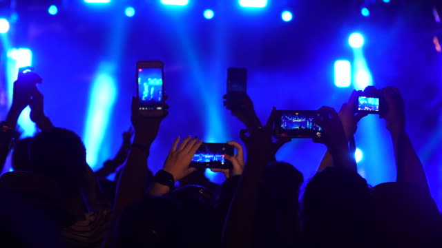 Group of music fans recording concert with mobile phones