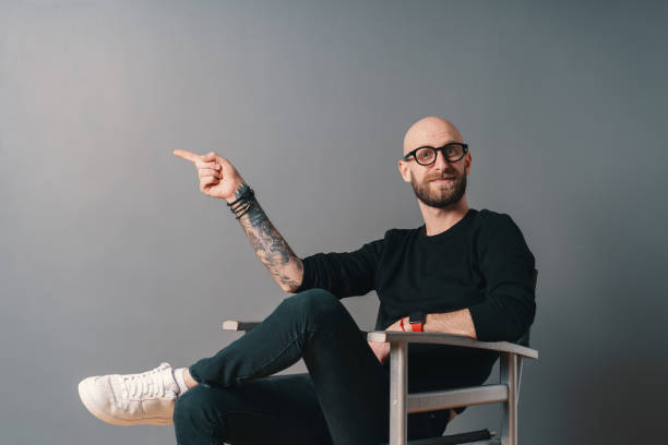 istock Modern young man pointing with finger on gray copy space 1199628478