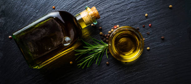 extra virgin olive oil in a glass bottle, flavored with rosemary and peppercorns - virgin olive oil imagens e fotografias de stock