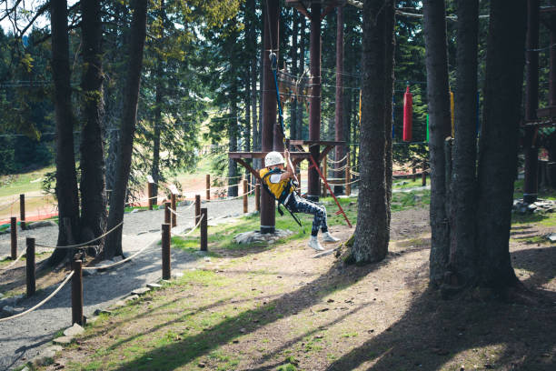 szczęśliwy dzieciak zabawy podczas zip podszewka w parku rozrywki. - zip lining zdjęcia i obrazy z banku zdjęć