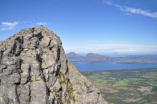 View to grey granite cliffs of Seven Sister mountains, Norway with Donna island and blue Norwegian sea in background on sunny summer day