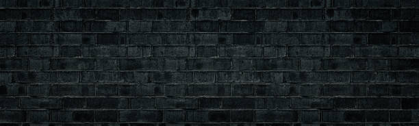 istock Wide black brick wall texture. Rough shabby brickwork widescreen backdrop. Dark gray panoramic gloomy grunge background 1199632745