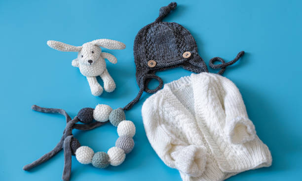 istock Knitted baby clothes and accessories on a blue background . 1199634225